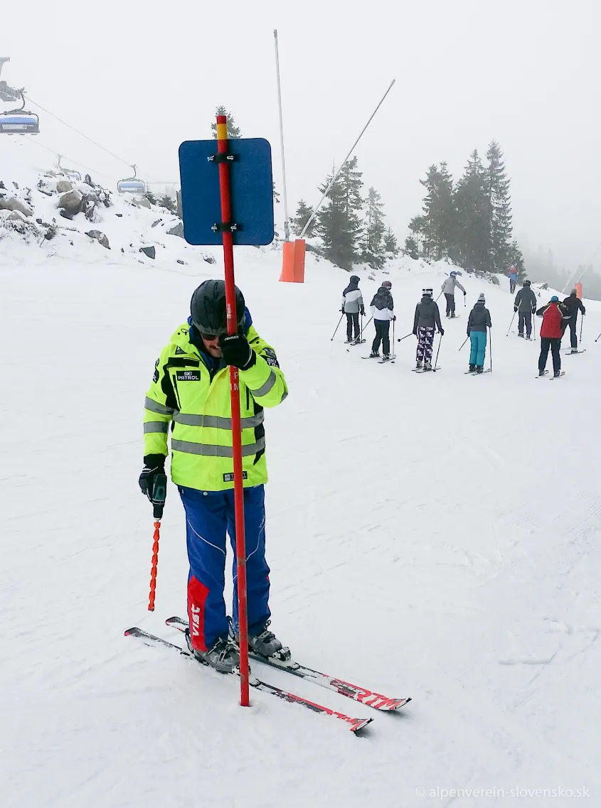 Skialpinista stúpajúci okrajom upravenej zjazdovky